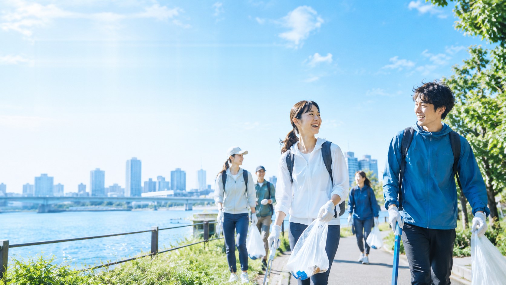 川沿いの遊歩道を、笑顔で話しながら歩き、清掃活動をする人々。背景に青空と街並み